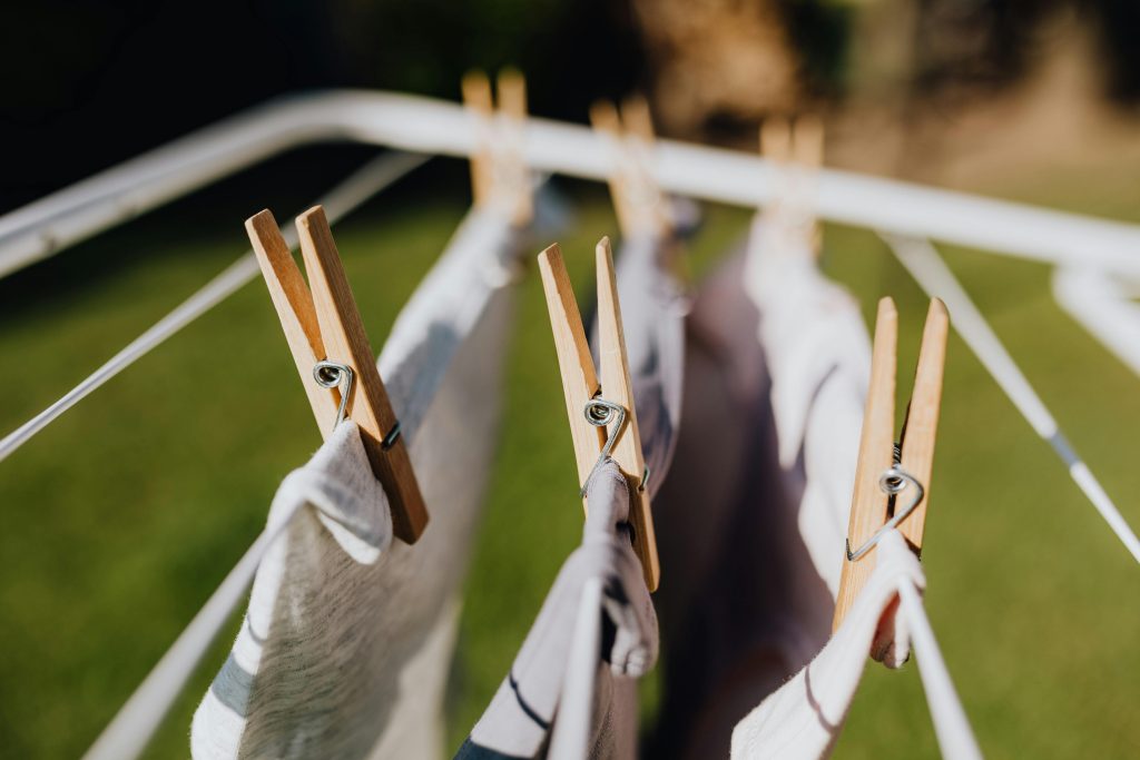 Wet lingerie with clothespins attached to metal folding clotheshorse placed on green lawn in garden